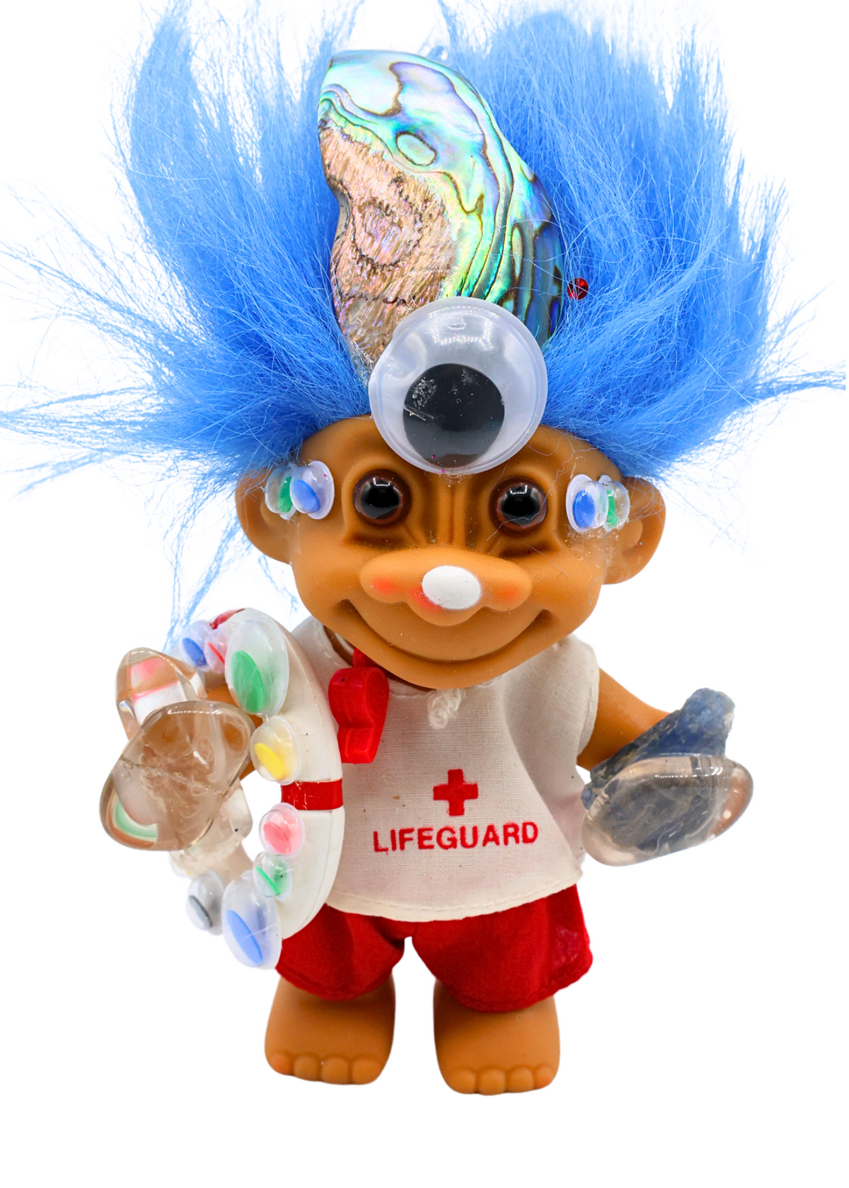 Close-up of Captain All-Seeing crystal troll doll with large third eye, blue hair, lifeguard outfit and abalone shell