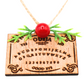 Close-up of wooden Ouija board holiday ornament with red bead and green sprigs
