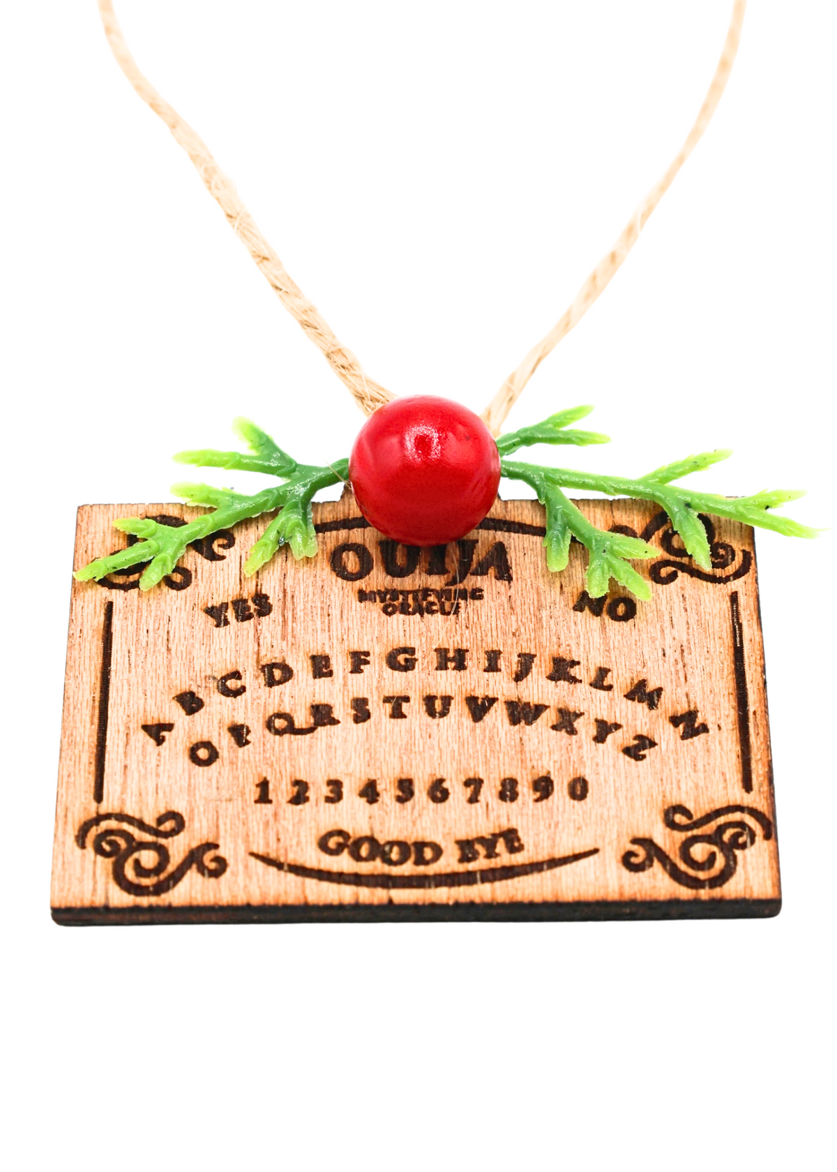 Close-up of wooden Ouija board holiday ornament with red bead and green sprigs